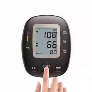 A digital blood pressure monitor with a large display, showing systolic, diastolic, and pulse readings, and a finger pressing the start button.